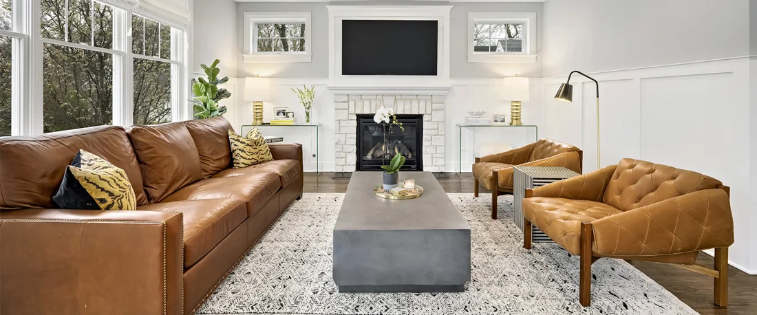 Sunlit living room with leather sofas, garden views and a white fireplace